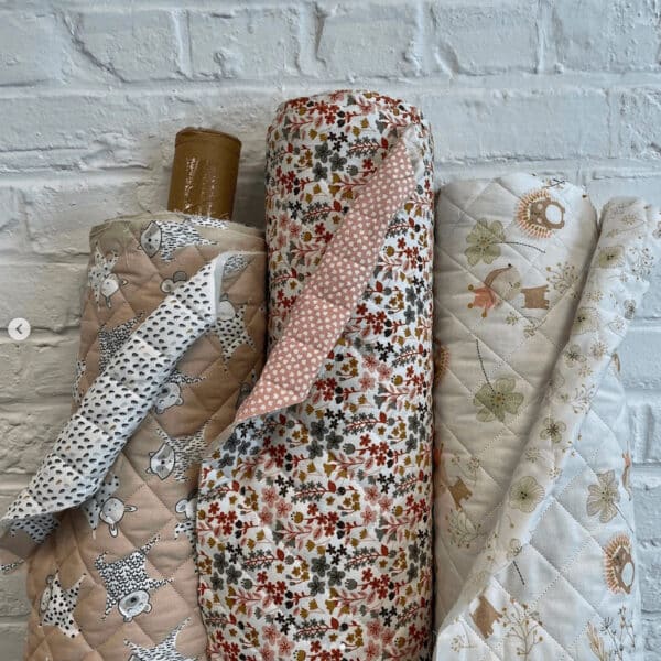 rolls of re- quilted double sided cotton fabric leaning against a white painted brick wll